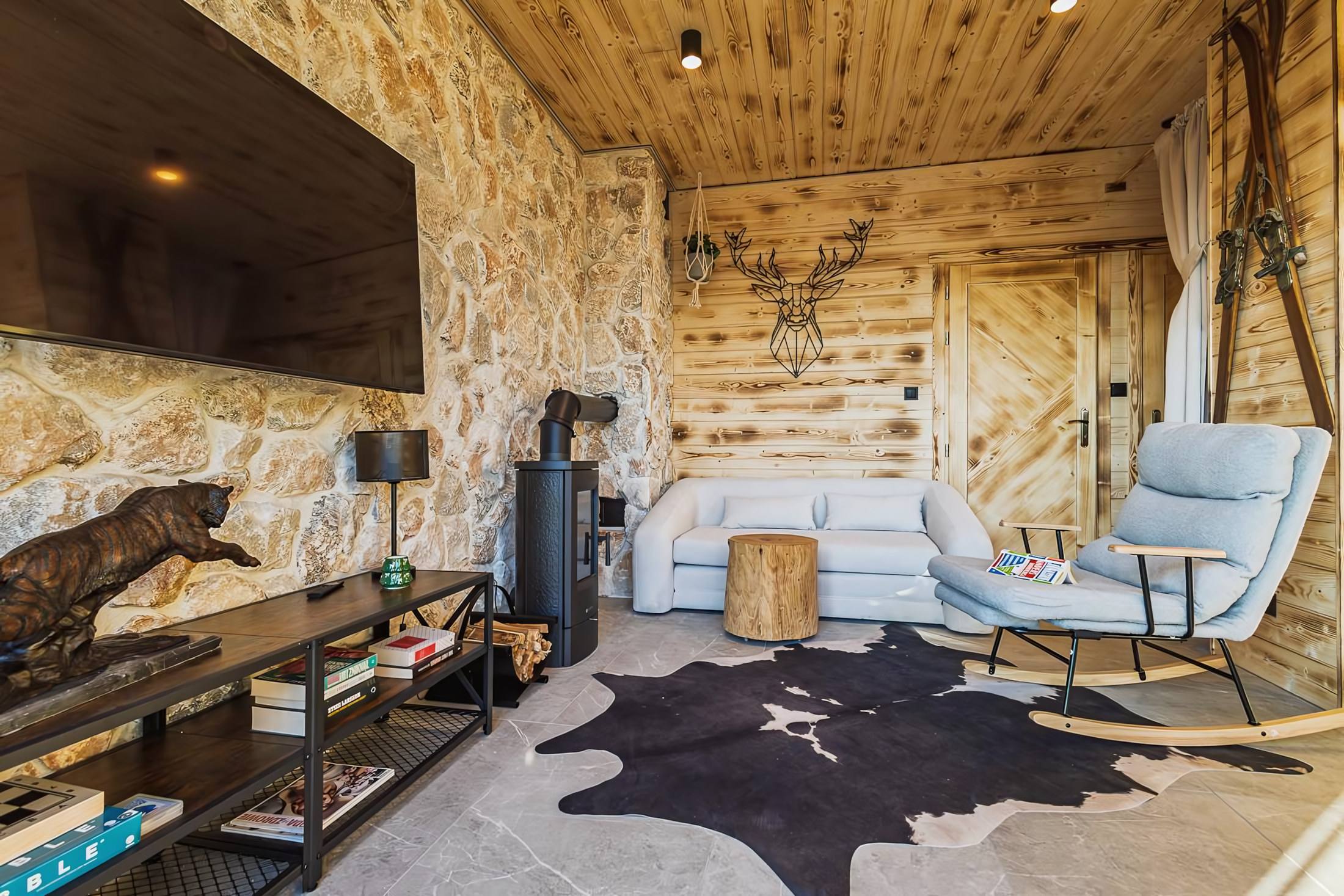 Salon z kamienną ścianą, kominkiem i bujanym fotelem
